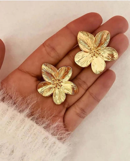 Held in hand, Love Language Earrings reveal the fine ridged texture of their gold flower petals up close.