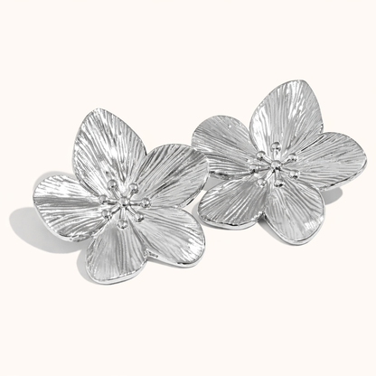 Love Language Earrings appear here in polished silver, their large textured flower petals catching the light.