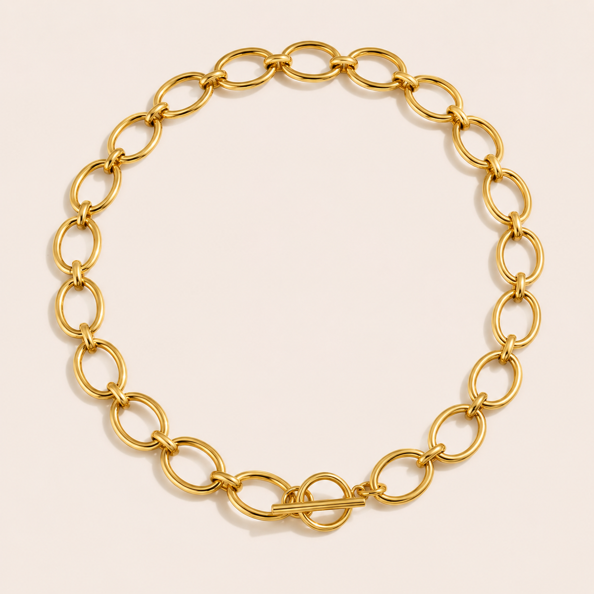 Gold oval-link chain necklace with a toggle clasp from the Loved and Lost NECKLACE design, laid flat on beige.