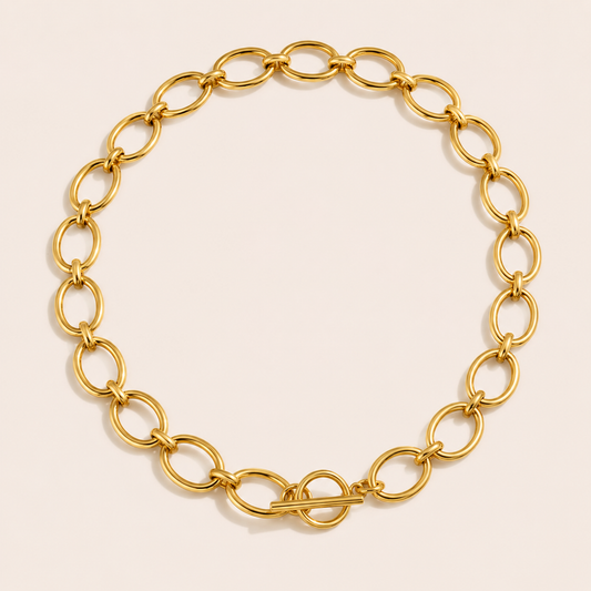 Gold oval-link chain necklace with a toggle clasp from the Loved and Lost NECKLACE design, laid flat on beige.