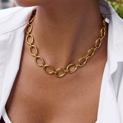 Model wears the gold Loved and Lost NECKLACE close to the neckline, paired with a white shirt over a burgundy top.