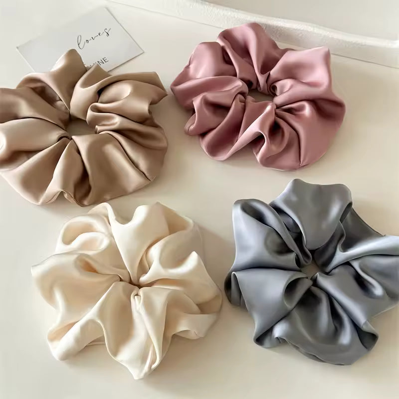 Lucia SCRUNCHIE XL flat-lay of four colors: taupe, mauve, cream and grey satin scrunchies on white.