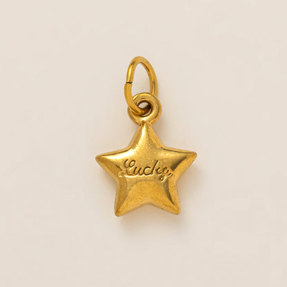 The Lucky Star CHARM in gold, a star-shaped pendant engraved with the word Lucky, shown in close-up studio photography.