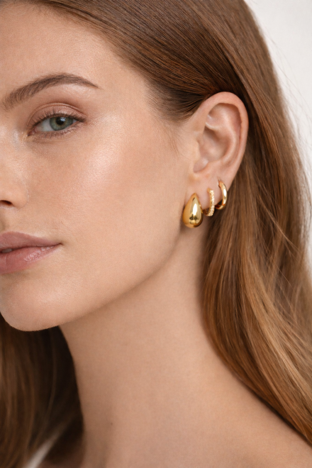 Lulu Set worn on the ear in gold, a teardrop hoop stacked closely with a pave hoop and a plain hoop.