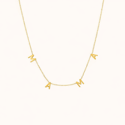 The Mama NECKLACE in gold, individual letters spelling MAMA dangling from a fine chain, shown on a cream background.