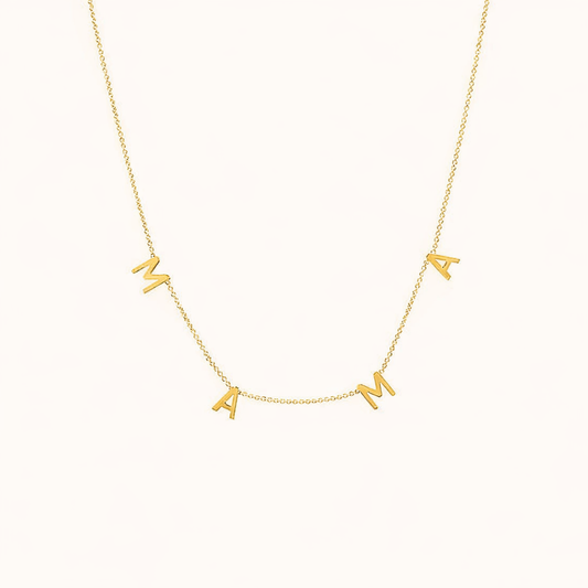 The Mama NECKLACE in gold, individual letters spelling MAMA dangling from a fine chain, shown on a cream background.