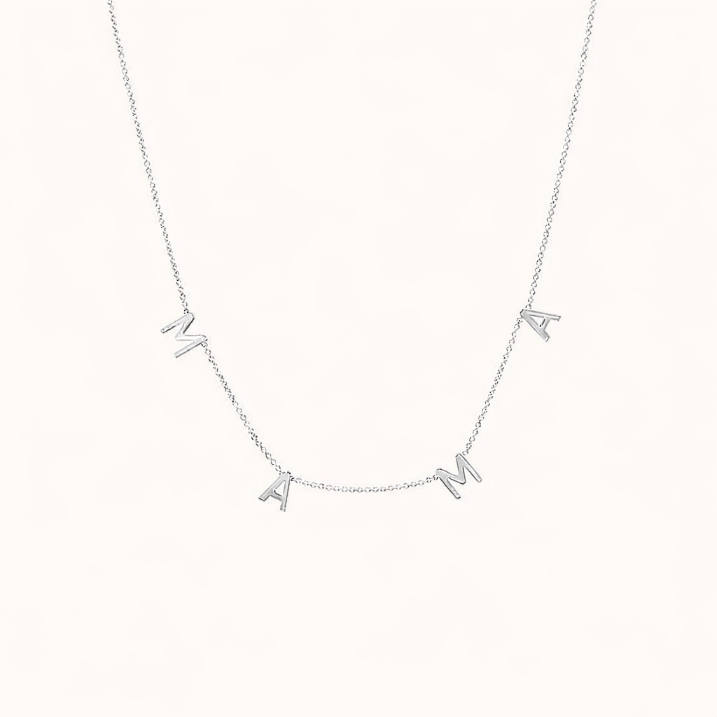 The Mama NECKLACE in silver, individual letters spelling MAMA dangling from a fine chain, shown on a cream background.