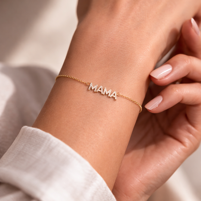 Mama Zirconia BRACELET worn on the wrist, close-up of the pave crystal MAMA charm on a white sleeve.