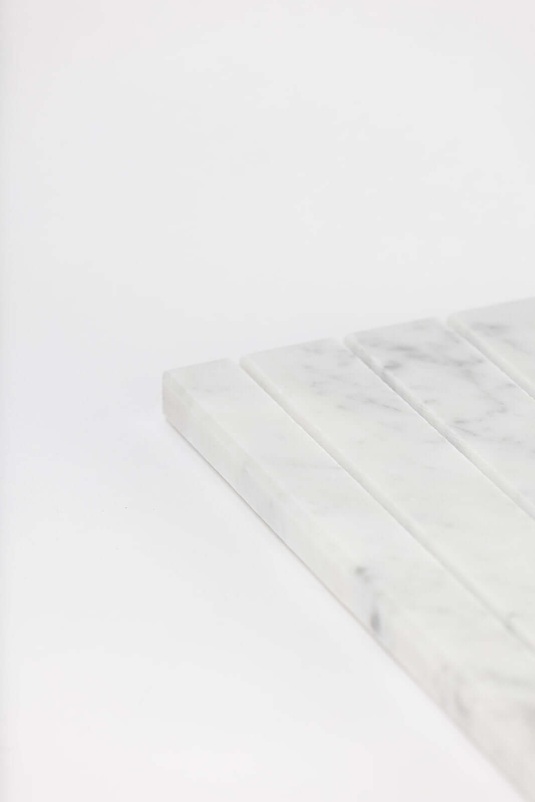 Close-up of the white marble tray's ridged slots showing its natural grey veining.