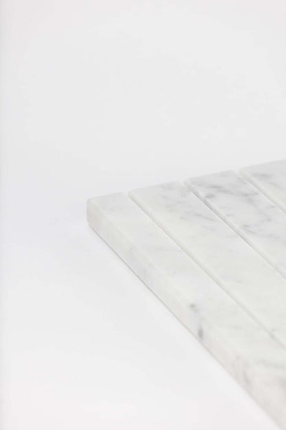 Close-up of the white marble tray's ridged slots showing its natural grey veining.