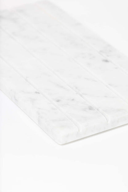Angled close-up of the white marble jewelry tray highlighting its ridged compartments and marble veining.