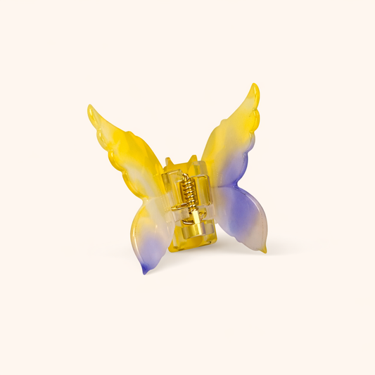 Yellow and blue ombré acetate butterfly-shaped claw clip from the Mariposa HAIR CLIP collection, on a cream background.
