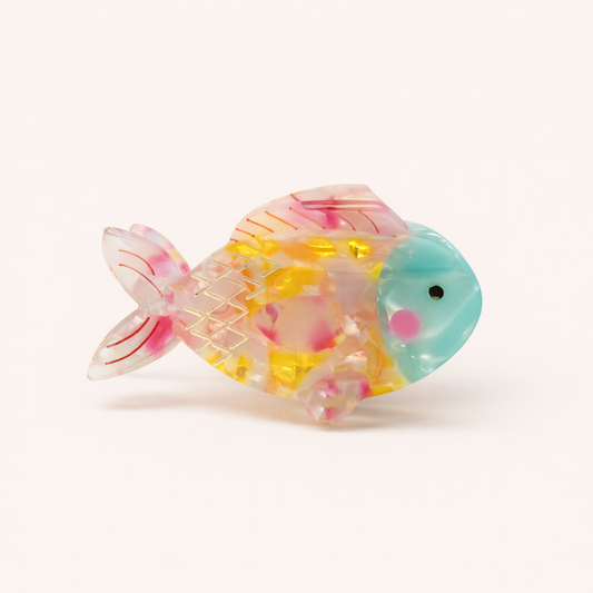 Marlin HAIR CLIP fish-shaped acetate claw clip in translucent pink and yellow with a teal head and gold zigzag scale detailing, studio shot.