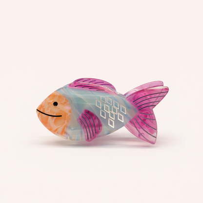 Marlin HAIR CLIP fish-shaped claw clip in translucent blue-grey with magenta fins, peach face, and white diamond scale details, studio shot.