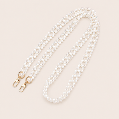 Folie à Trois Marnie Pearl long wholesale phone chain in a woven diamond pattern of white pearls with gold clasps, coiled on a cream background.