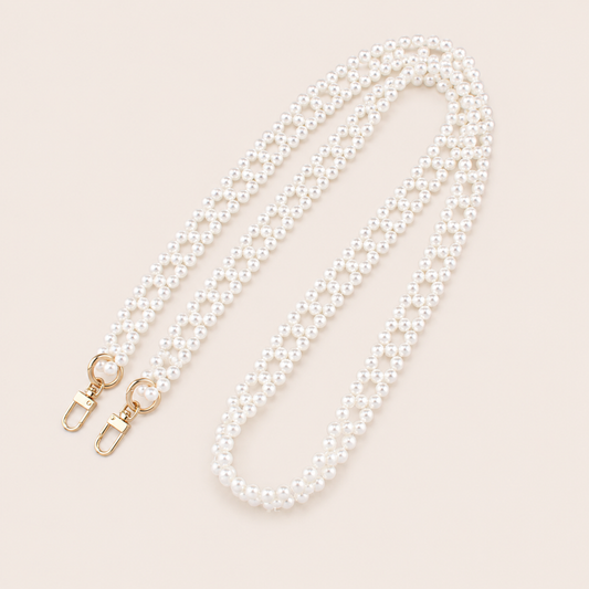 Folie à Trois Marnie Pearl long wholesale phone chain in a woven diamond pattern of white pearls with gold clasps, coiled on a cream background.