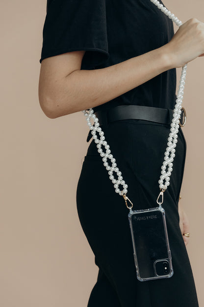 Model in black holding a phone in a clear case on the Folie à Trois Marnie Pearl wholesale phone chain, shown crossbody at the hip.