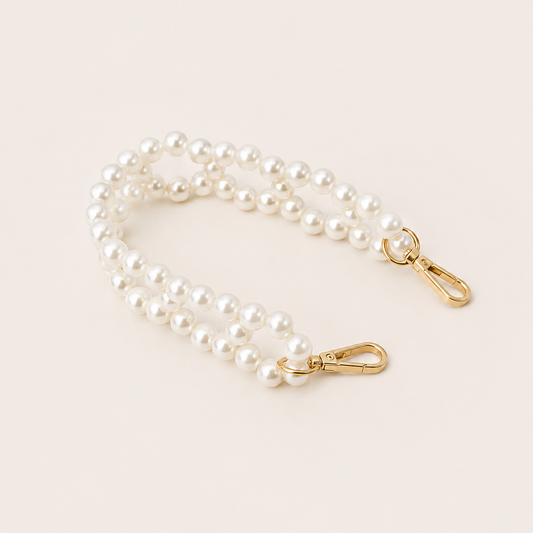 Folie à Trois Marnie Pearl short wholesale phone chain in a double strand of white pearls with gold clasps, coiled on a cream background.