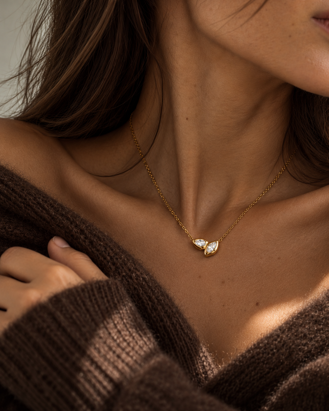 Gold Marquise NECKLACE with a sparkling double-marquise pendant on a bare collarbone, worn with an off-shoulder brown knit