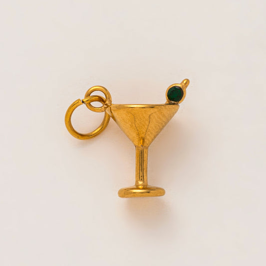 The Martini Glass CHARM in gold, a cocktail glass pendant with a green zircon olive garnish, shown in close-up studio photography.