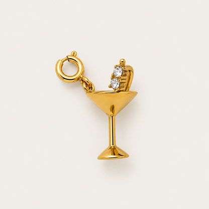 The gold Martini Glass CHARM with a two-zircon olive pick and spring ring clasp, shown in close-up on a cream background.