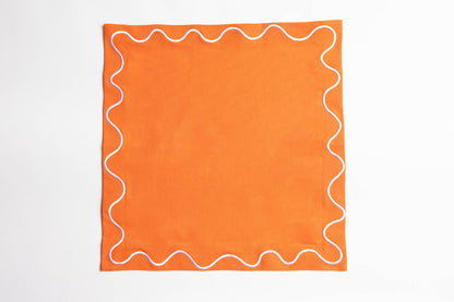 Single orange Maude napkin with a white wave-trim border, laid flat and square on a white background.