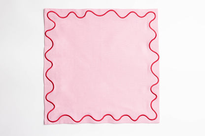 Single pink Maude napkin with a red wave-trim border, laid flat and square on a white background.