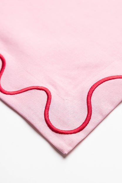 Close-up corner detail of an olive-green Maude napkin showing its cream scalloped wave-trim embroidery stitching.