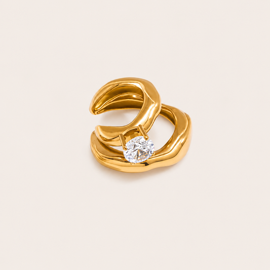 The Maya EAR CUFF in gold, a sculptural double-band cuff set with a single round clear gem, shown in a studio close-up.