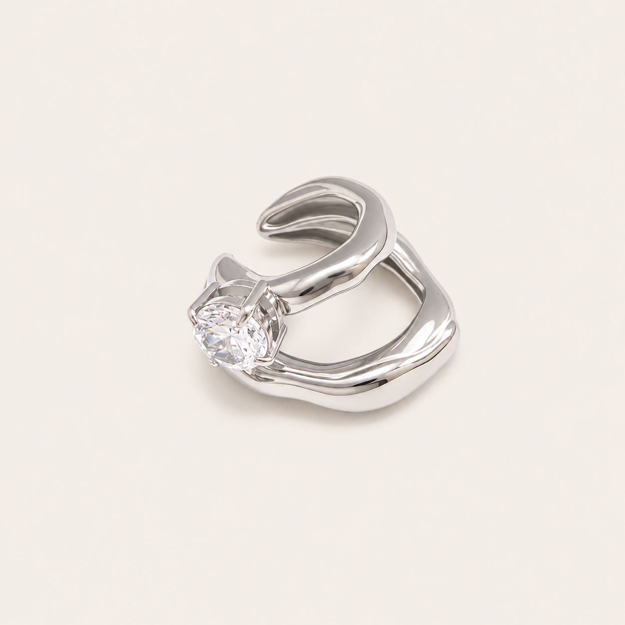 The Maya EAR CUFF in silver, a sculptural double-band cuff set with a single round clear gem, shown in a studio close-up.