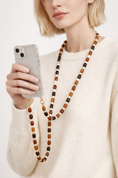 Model wears the brown beaded Meryn chain crossbody, holding a clear case phone in her hand.