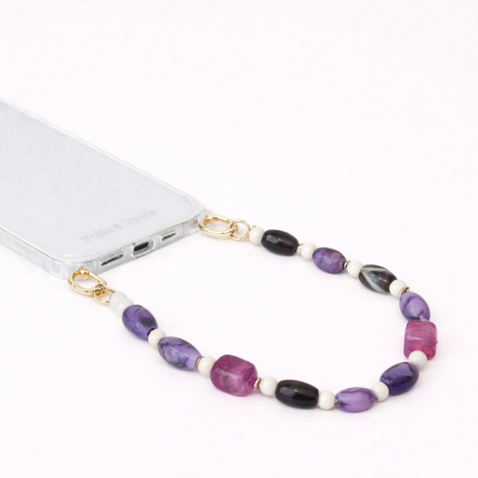 Purple, black, and magenta beaded Meryn SHORT PHONE STRAP clipped to a clear phone case with gold hardware.