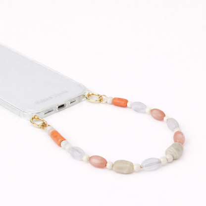 Gray, coral, and peach beaded Meryn SHORT PHONE STRAP clipped to a clear phone case with gold hardware.