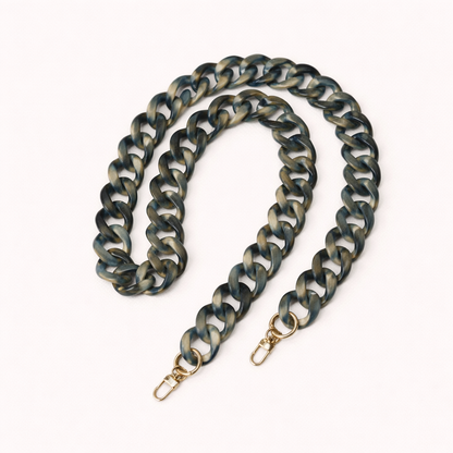 A coiled blue-grey and gold marbled acrylic curb-link phone chain with gold clasps, shown on a cream background.