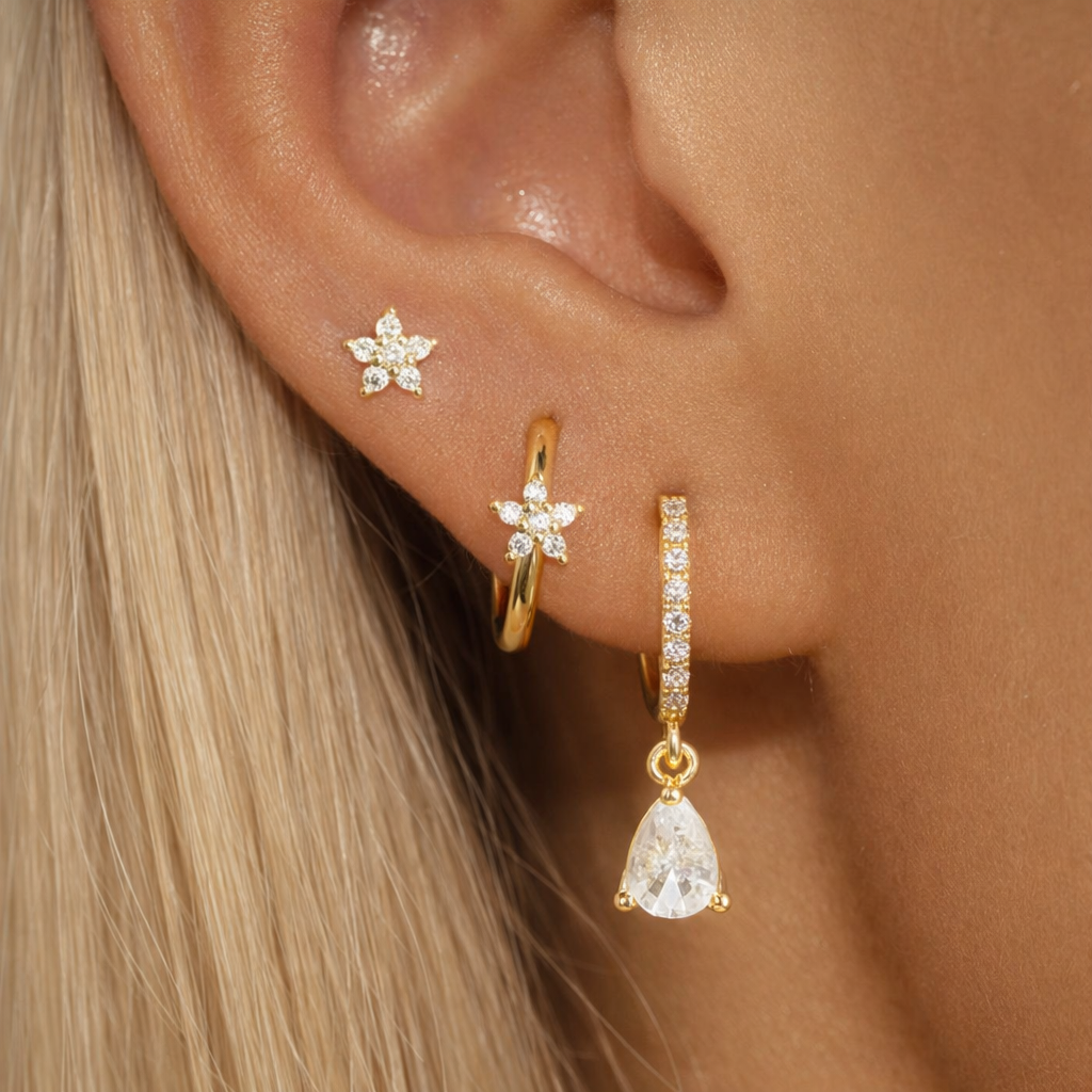 Worn along the ear, the Mica SET layers a flower stud, pave hoop with teardrop drop, and flower huggie.