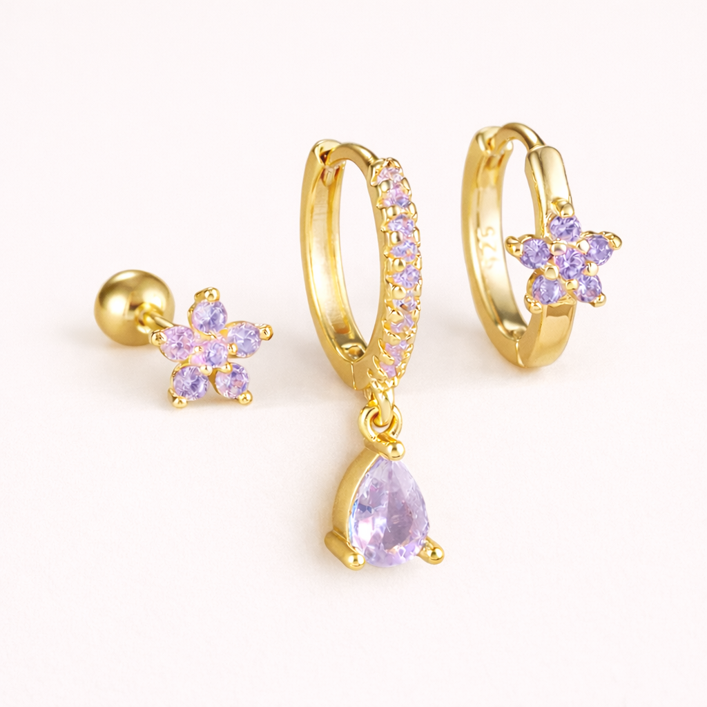 The Mica SET is shown in a purple crystal colorway across its flower stud, drop hoop, and flower huggie.