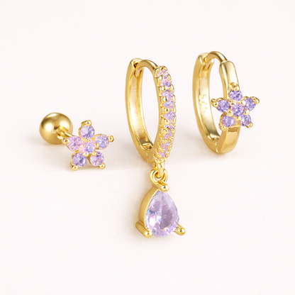 The Mica SET is shown in a purple crystal colorway across its flower stud, drop hoop, and flower huggie.