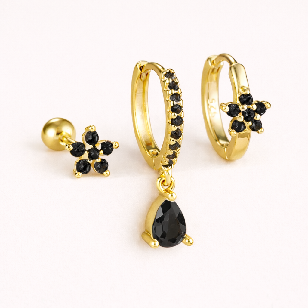 The Mica SET is shown in a black crystal colorway across its flower stud, drop hoop, and flower huggie.