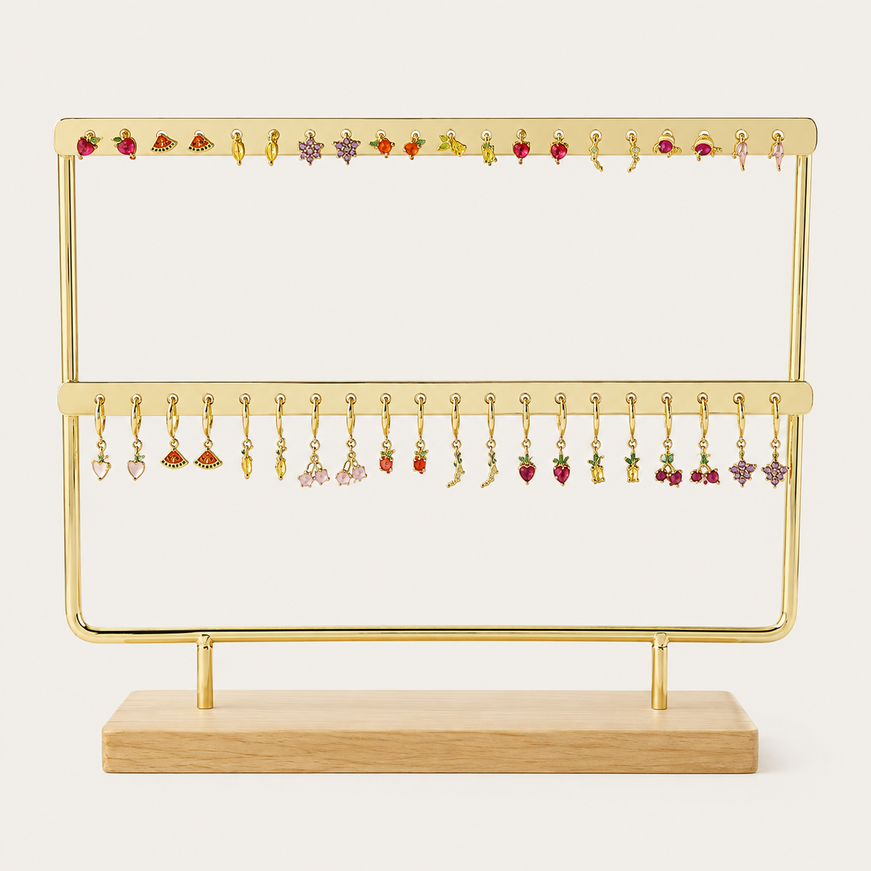 The Mini Folie 20-pieces BUNDLE on a gold stand, showing an assortment of fruit and charm stud earrings paired with matching dangle hoops.