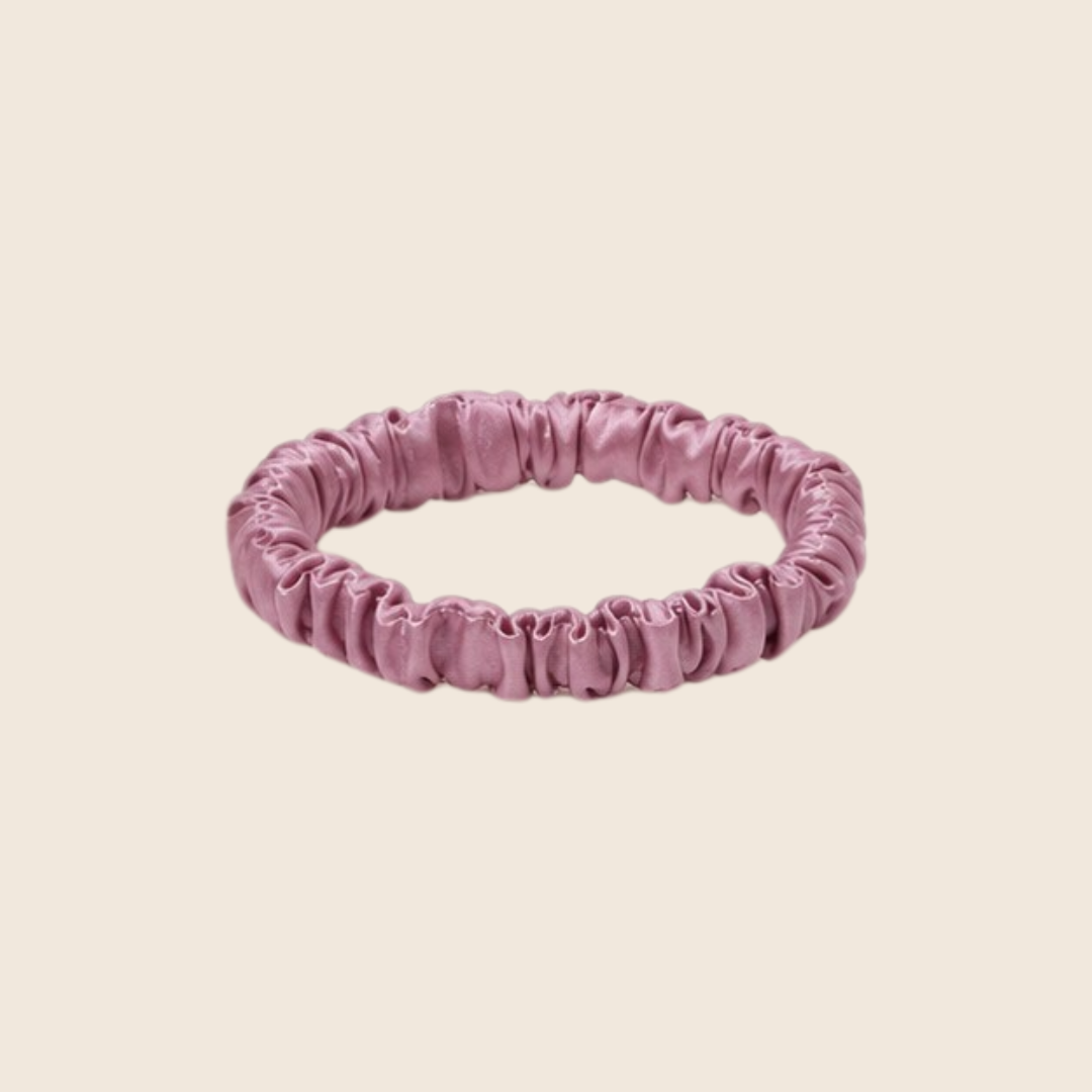 Minnie SCRUNCHIE S small satin scrunchie in purple, studio shot on a light beige background.