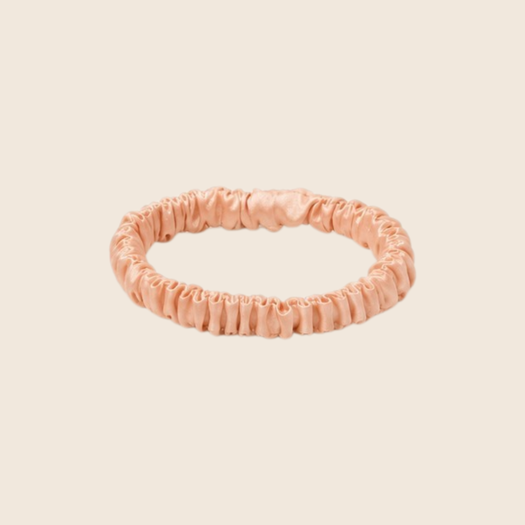 Minnie SCRUNCHIE S small satin scrunchie in peach, studio shot on a light beige background.
