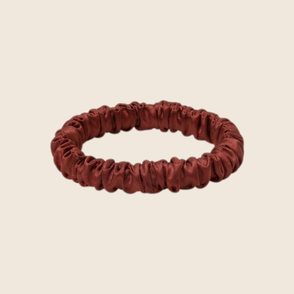 Minnie SCRUNCHIE S small satin scrunchie in burgundy, studio shot on a light beige background.