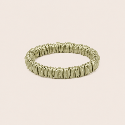 Minnie SCRUNCHIE S small satin scrunchie in sage green, studio shot on a solid pale pink background.