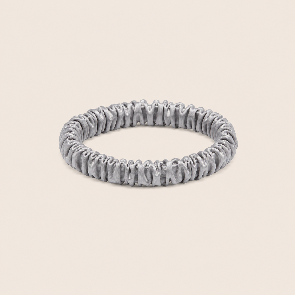 Minnie SCRUNCHIE S small satin scrunchie in silver, studio shot on a light beige background.