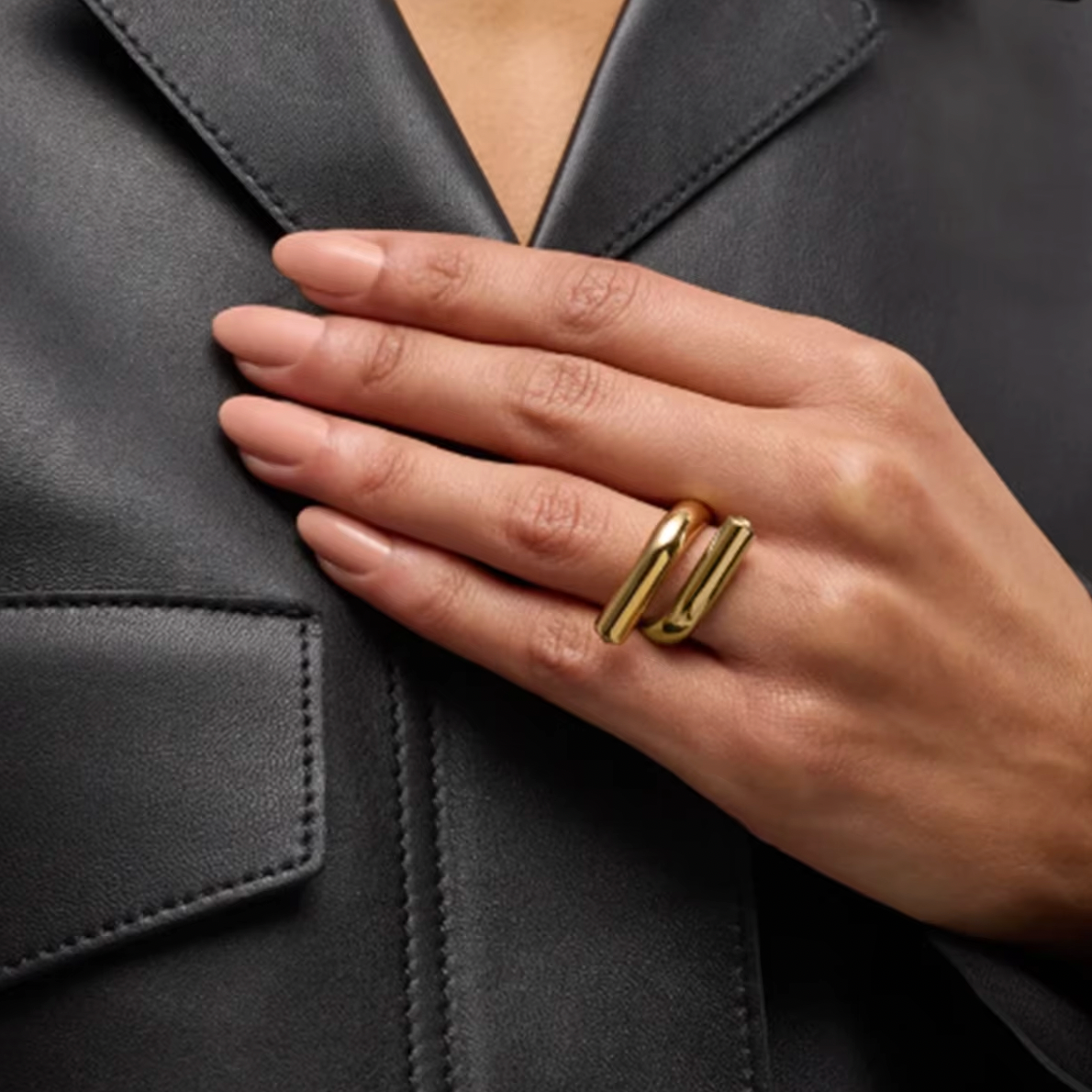 Model wears the gold Mischa RING with its parallel-bar design, hand resting on her leather jacket.