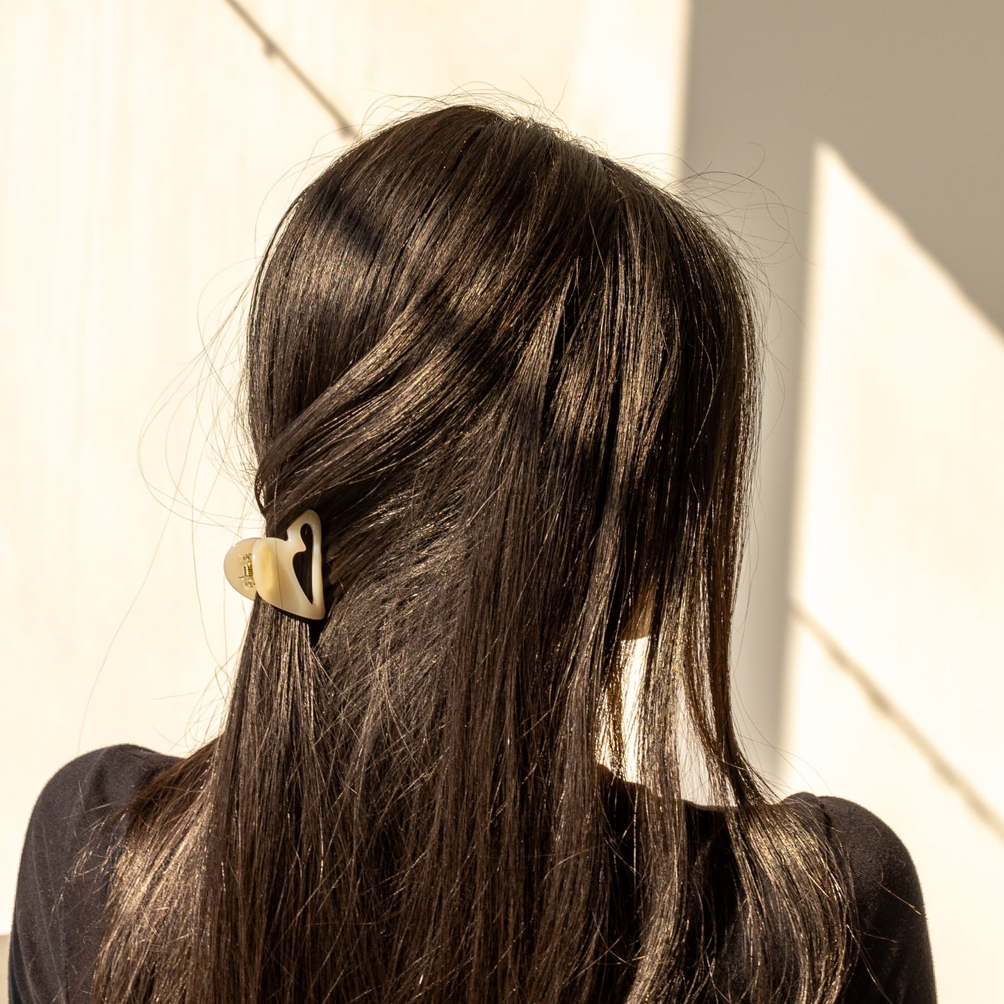 Mon Cœur HAIR CLIP in cream, worn holding a half-up style on dark hair, back view in sunlight.
