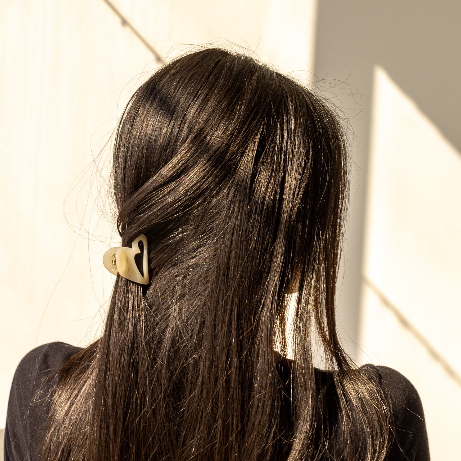 Mon Cœur HAIR CLIP in cream, worn holding a half-up style on dark hair, back view in sunlight.