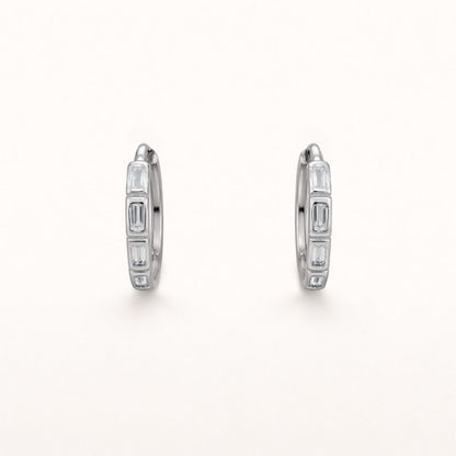 Monday To Friday Earrings set a row of alternating baguette-cut clear stones into a polished silver hoop.