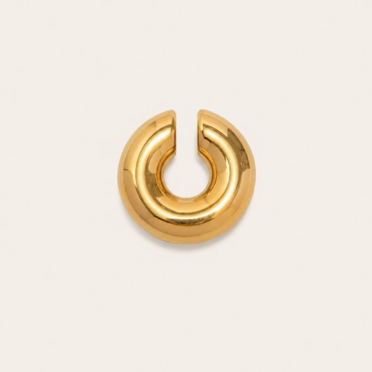 The Moon EAR CUFF in a studio flat lay, a smooth gold open-ended tube cuff shown from the front on cream.