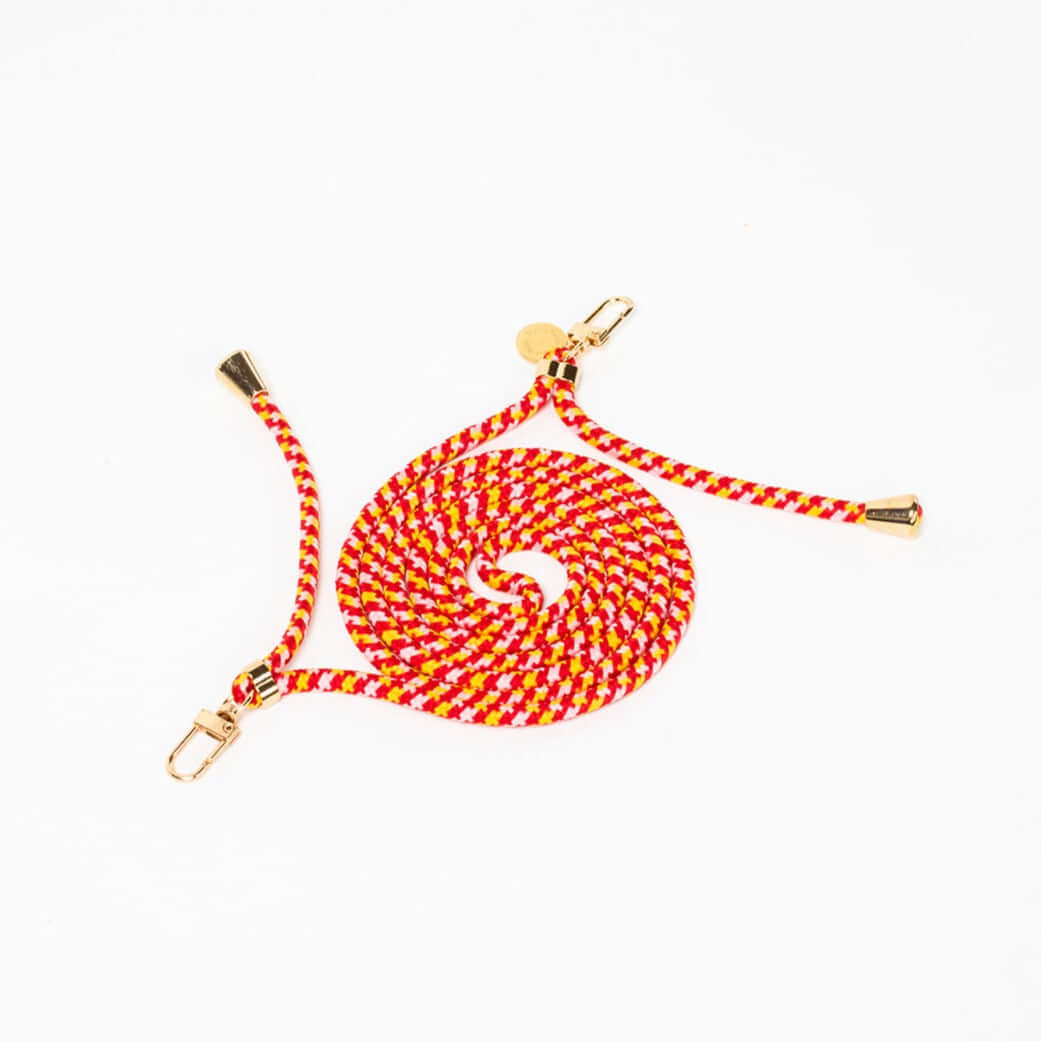 Red, yellow and white patterned Multi Colorful PHONE CORD coiled with gold-tone hardware on a white background.